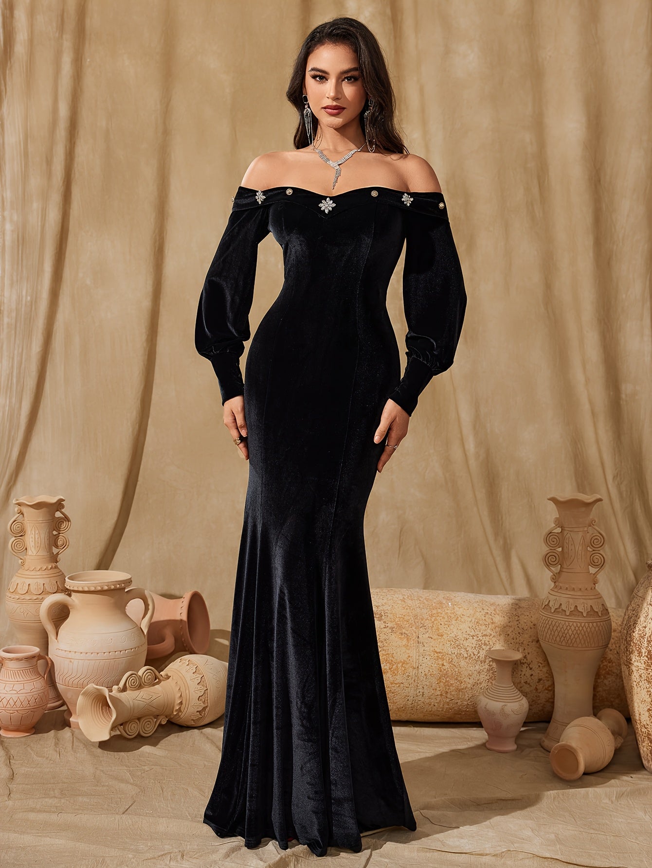 Vestido elegante de veludo estilo sereia com ombros à mostra e mangas compridas.